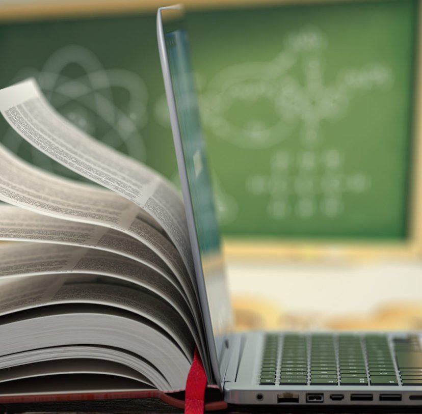 E-learning online education or internet encyclopedia concept. Open laptop and book compilation in a classroom.